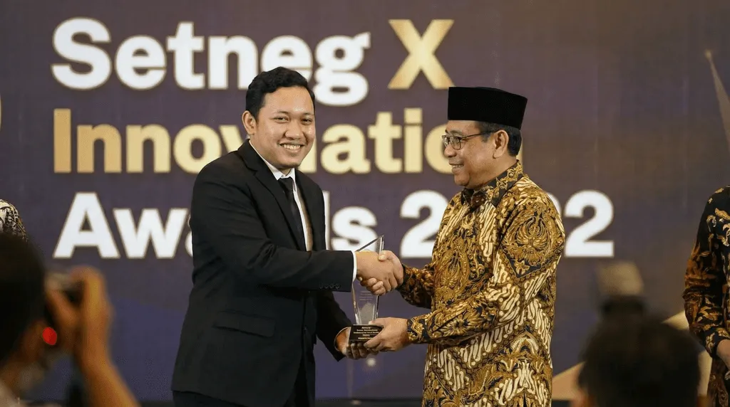 person discussing while standing in front of a large screen in front of people inside dim-lighted room